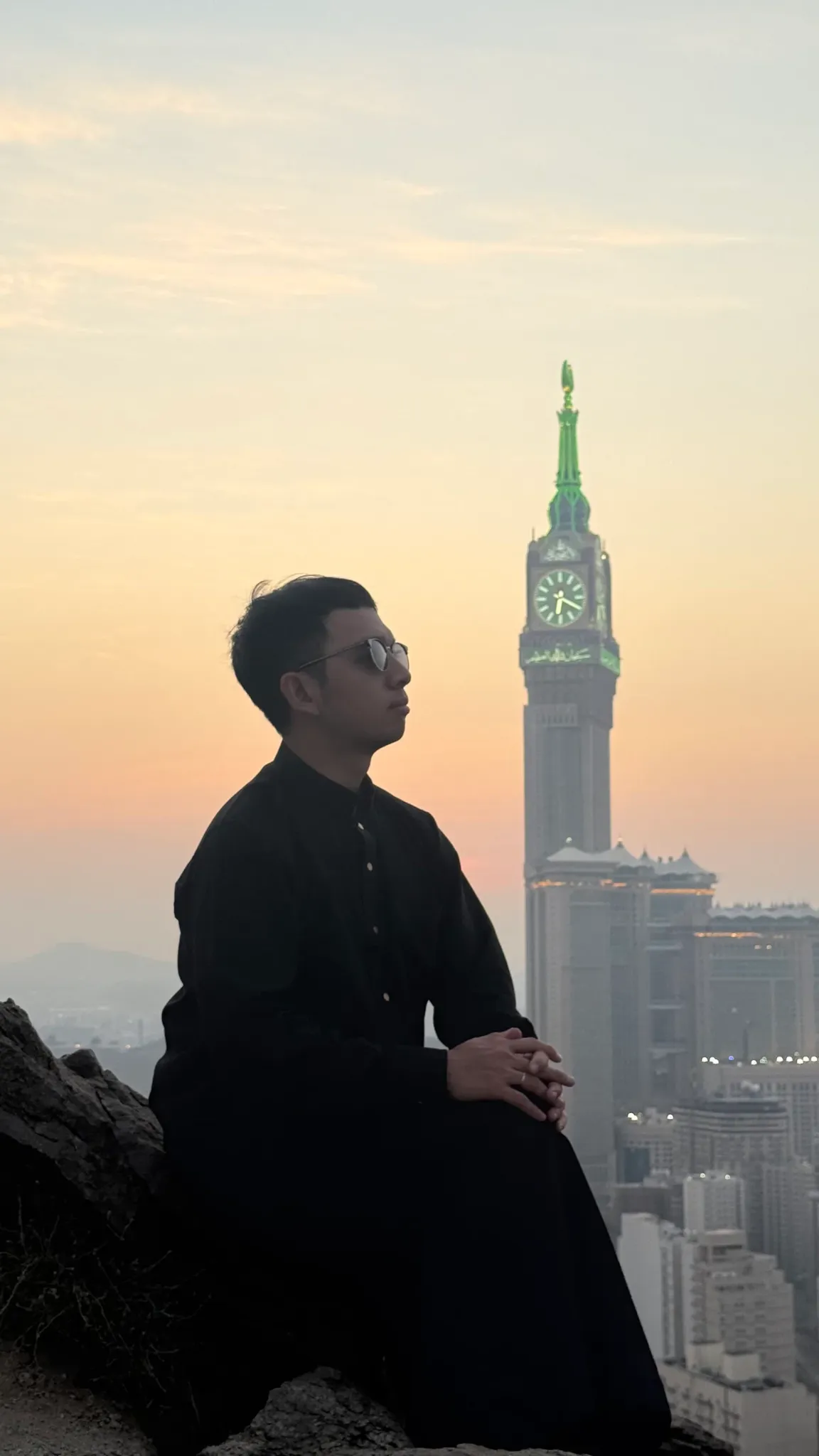 Potret jamaah dengan latar menara jam Makkah saat senja